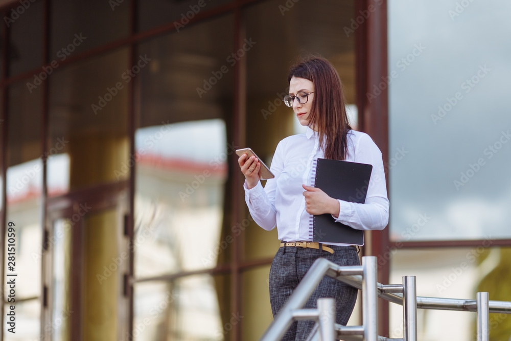 穿着白衬衫的年轻商务女性在户外使用智能手机。女性阅读短信