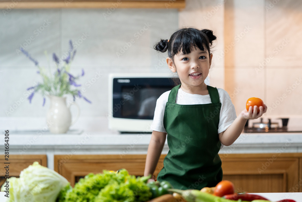 Asian kid in the kitchen at home. Kid enjoy cooking the healthy food with variety of vegetable.