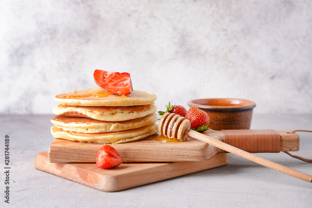 Tasty pancakes with strawberry and honey on table