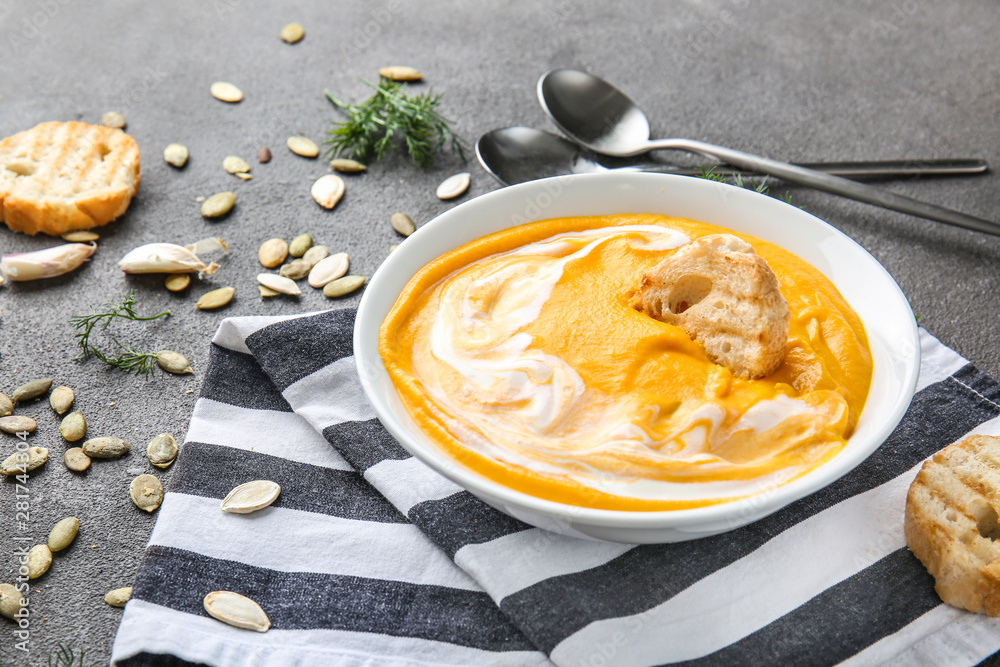 Bowl of tasty cream soup on grey table