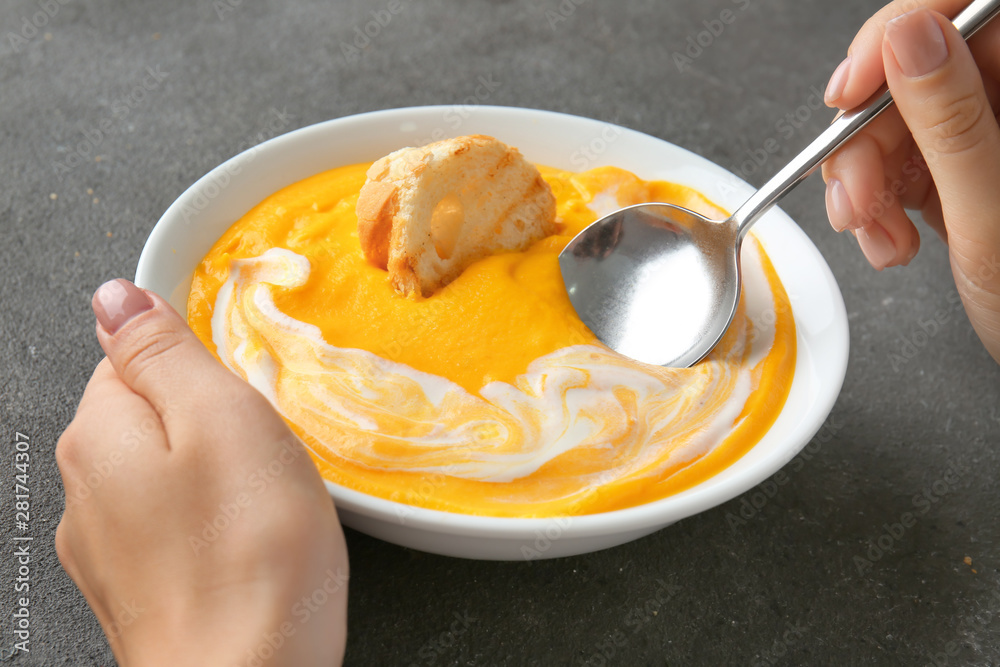 Woman eating tasty cream soup at table, closeup