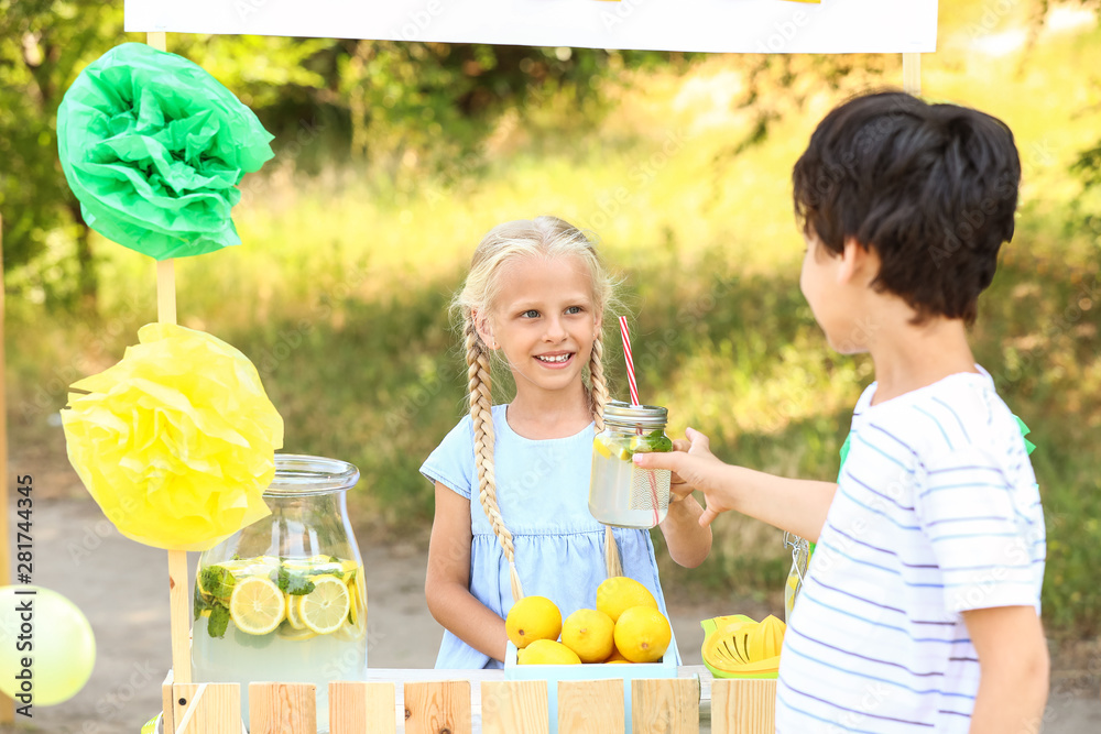 Cute little girl selling lemonade in park