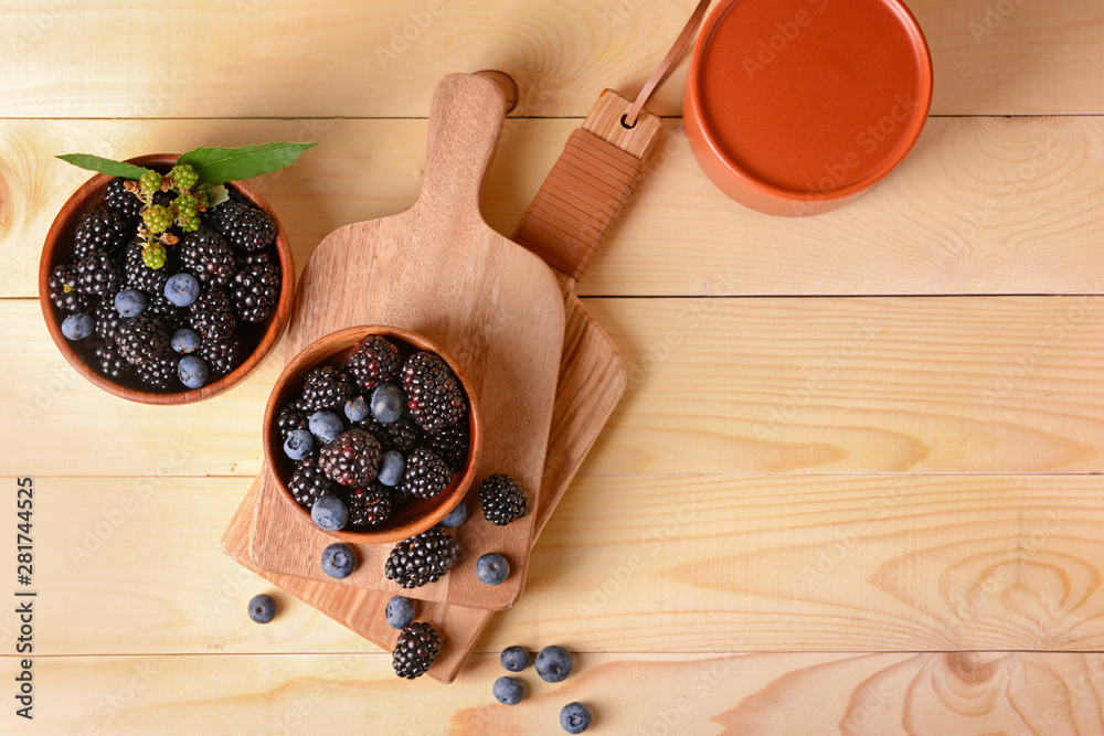 Bowls with tasty blackberries and blueberries on wooden table