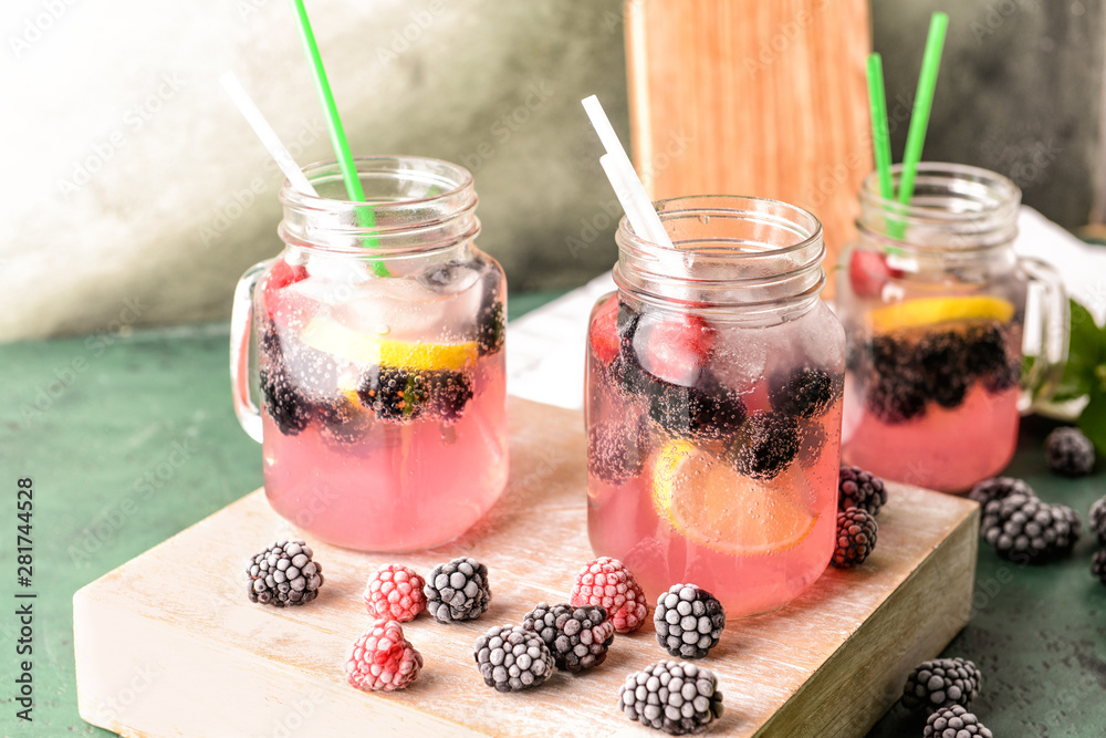 Mason jars of tasty blackberry lemonade on table