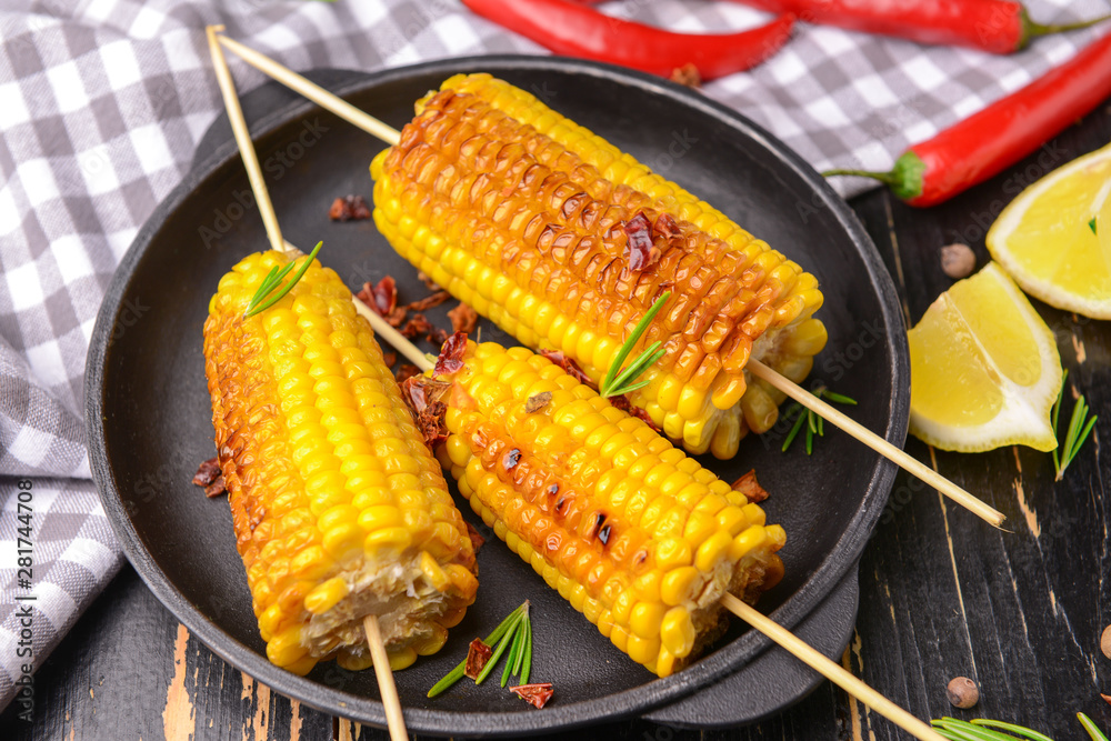 Plate with tasty grilled corn cobs on table