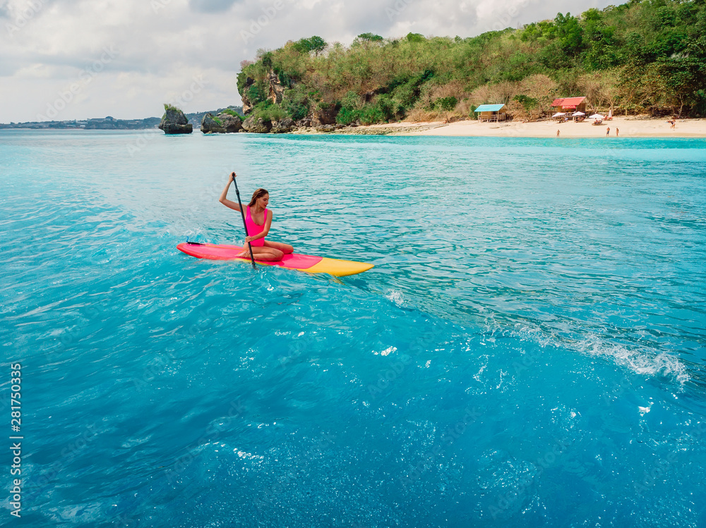 Aerial view of woman on stand up paddle board in ocean.