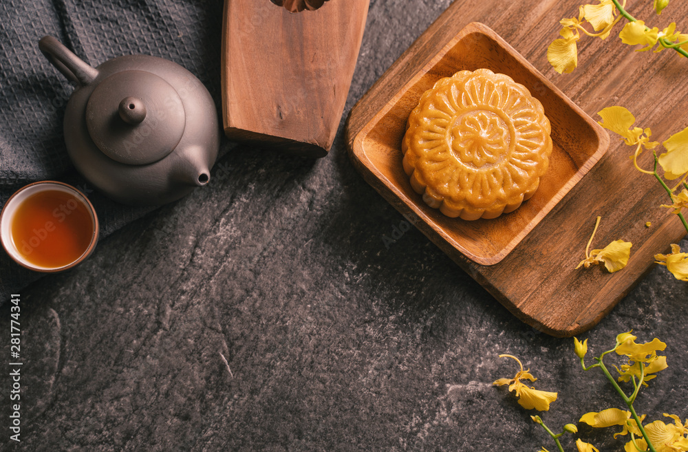 Mid-Autumn Festival traditional food concept - Beautiful Moon cake on black slate table with tea, pa