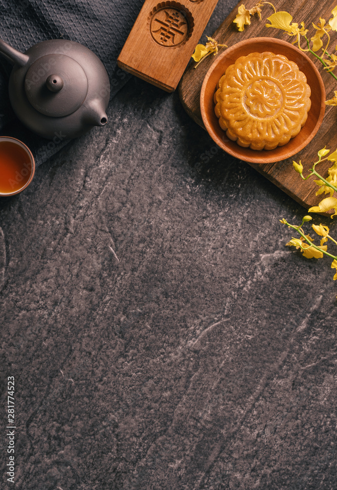 Mid-Autumn Festival traditional food concept - Beautiful Moon cake on black slate table with tea, pa