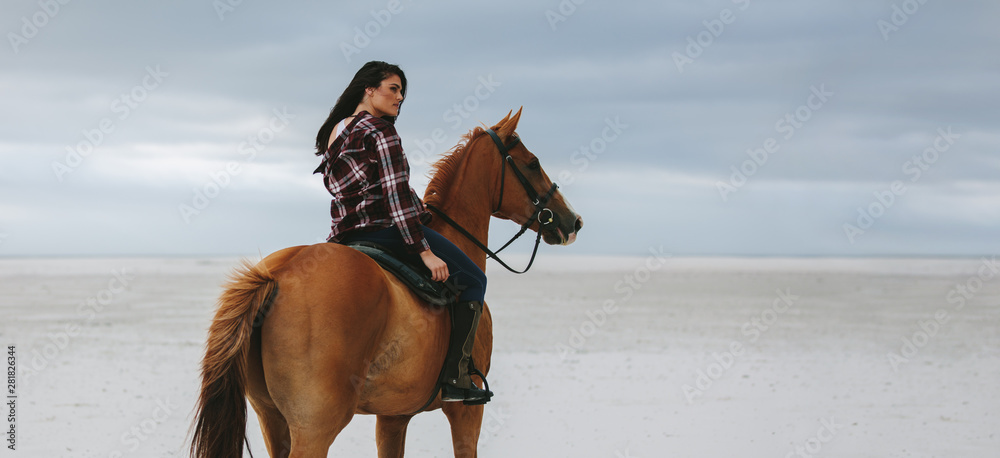 Cowgirl riding on horse at beach