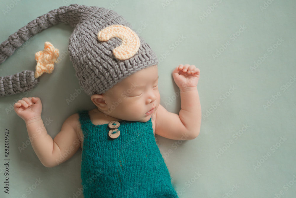 Adorable newborn baby sleeping in cozy room. Cute happy infant baby portrait with sleepy face in bed