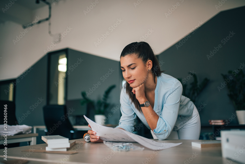 漂亮的年轻女人靠在桌子上，看着家具组装说明。