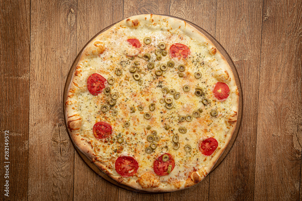 Top view of homemade pizza with tomato, olive, cheese and other ingredients.