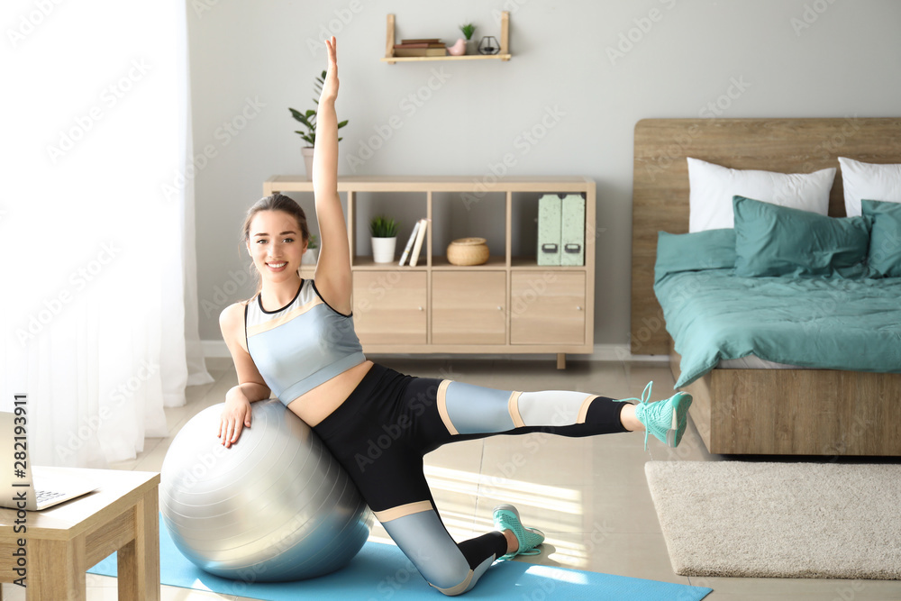 Young woman doing exercise with fitball at home