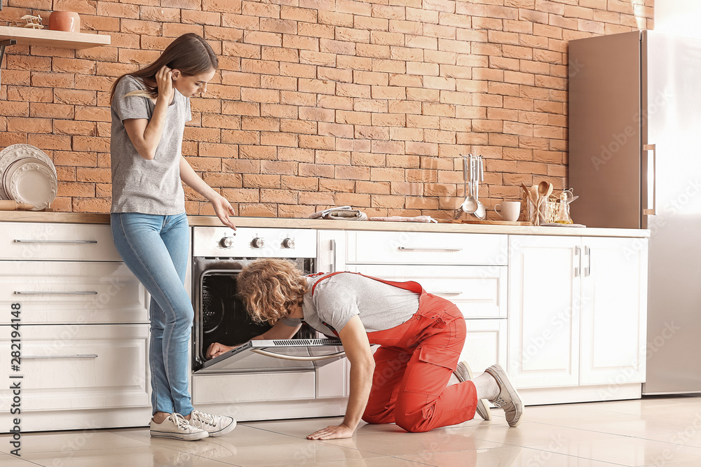 Worker repairing oven in kitchen