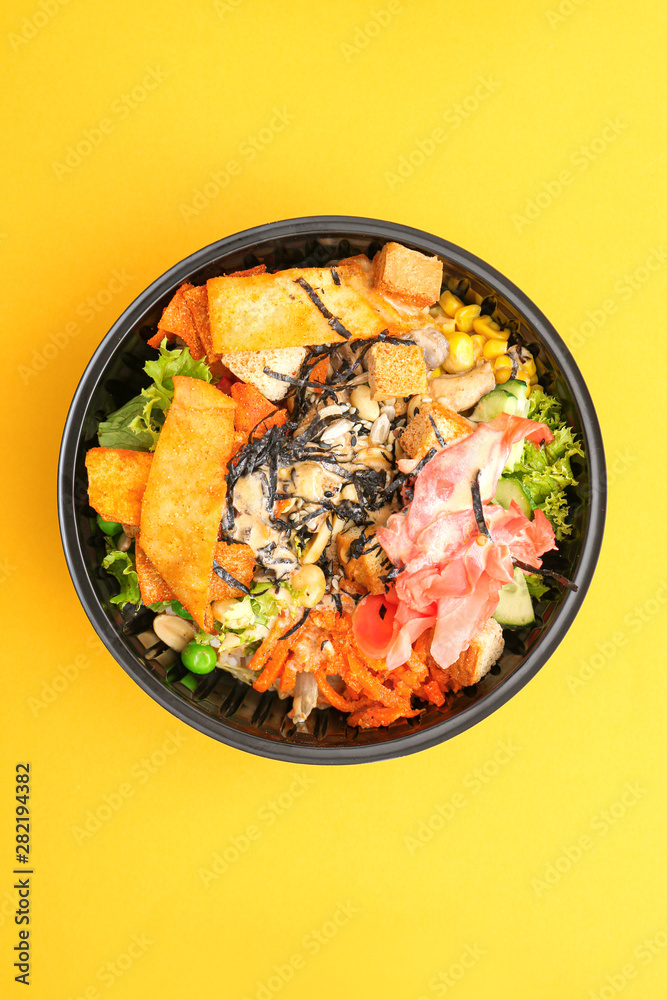 Container with delicious food on color background