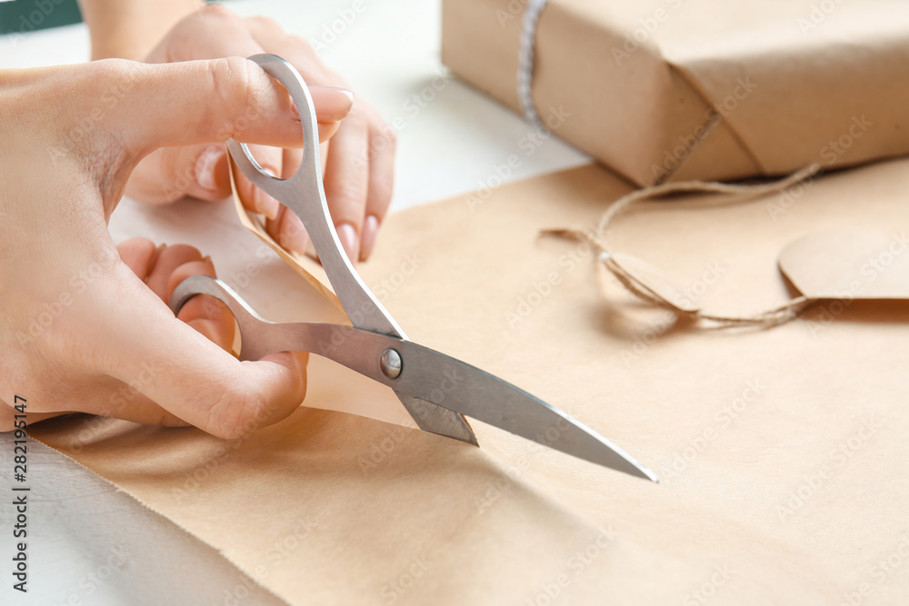 Woman cutting wrapping paper at table, closeup