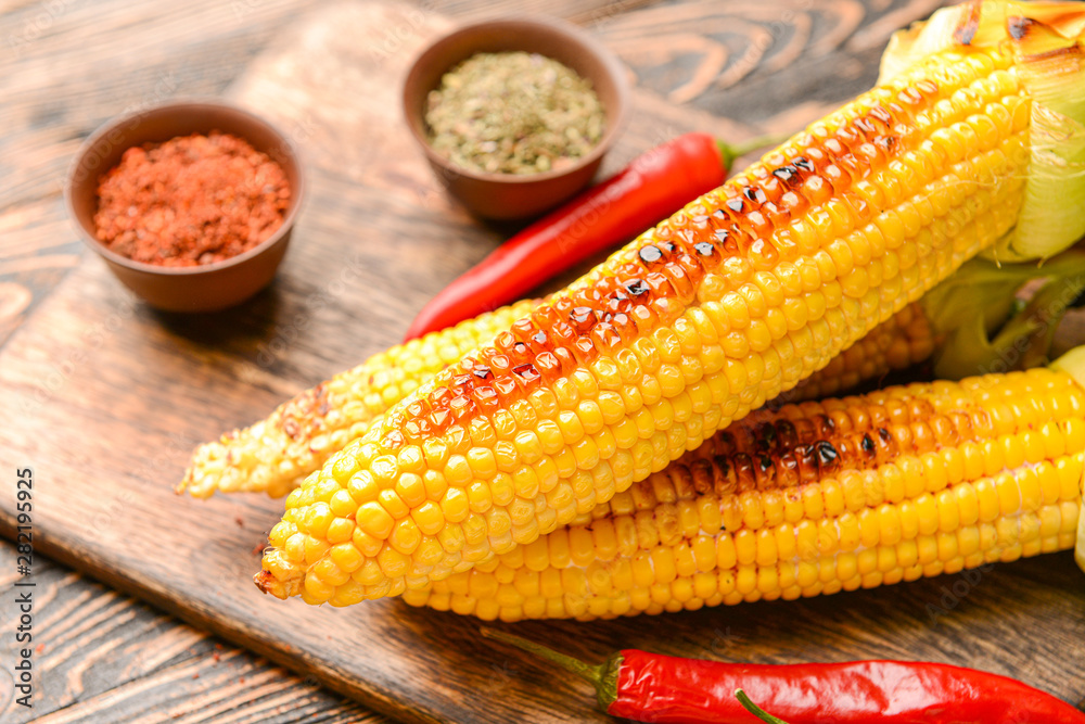 Tasty grilled corn cobs on wooden background