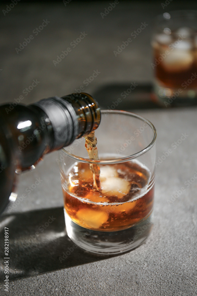 Pouring of whiskey in glass on table