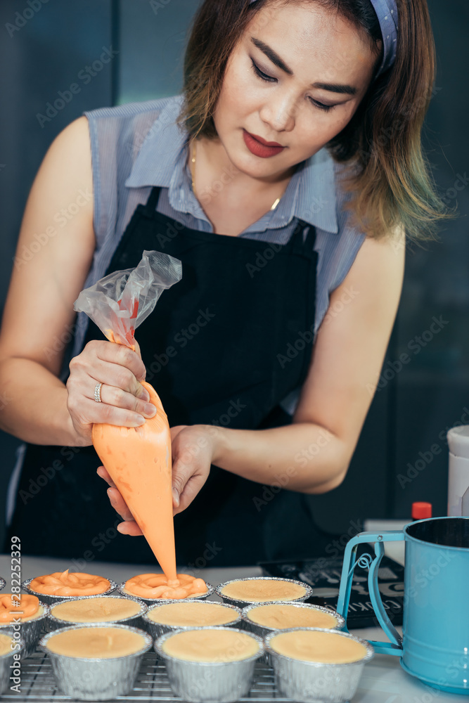 Asian women are using the mixture and help the cream for making the birthday cake for their family o