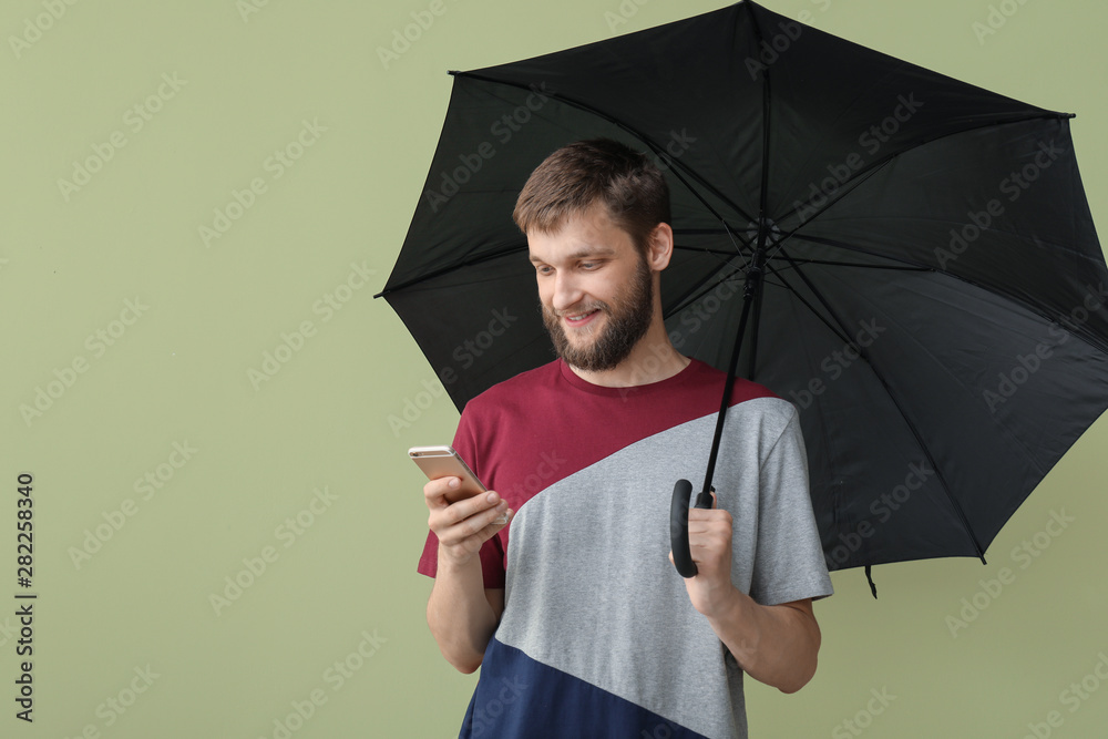 带雨伞和手机的英俊男子，背景为彩色