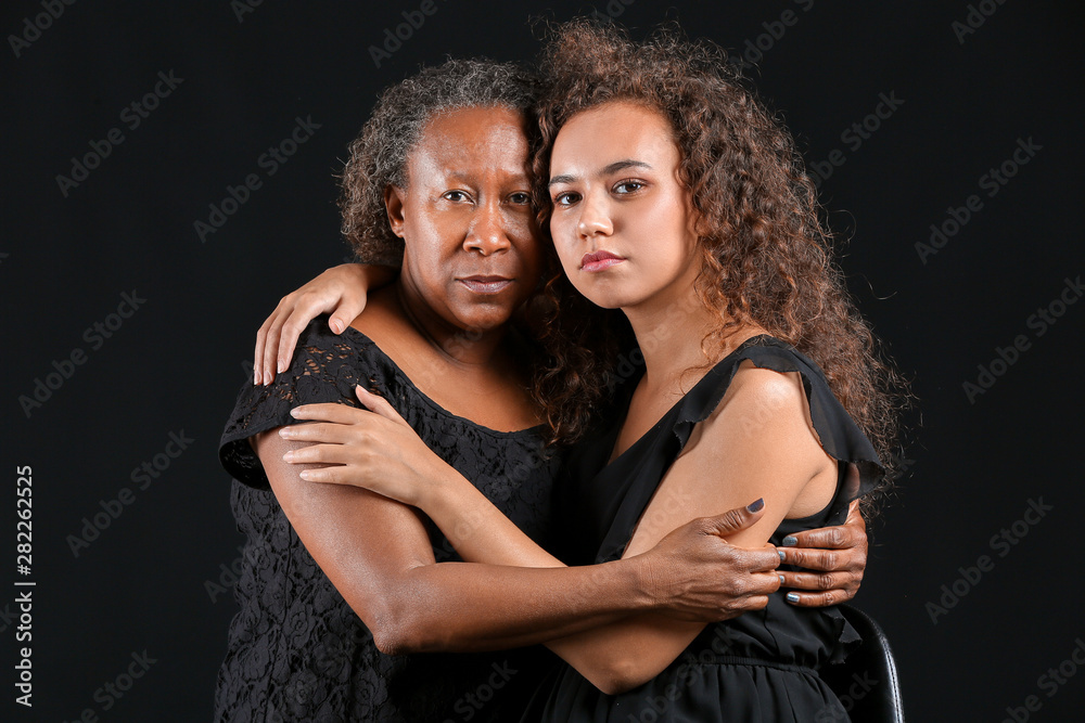 Portrait of African-American woman with her daughter on dark background