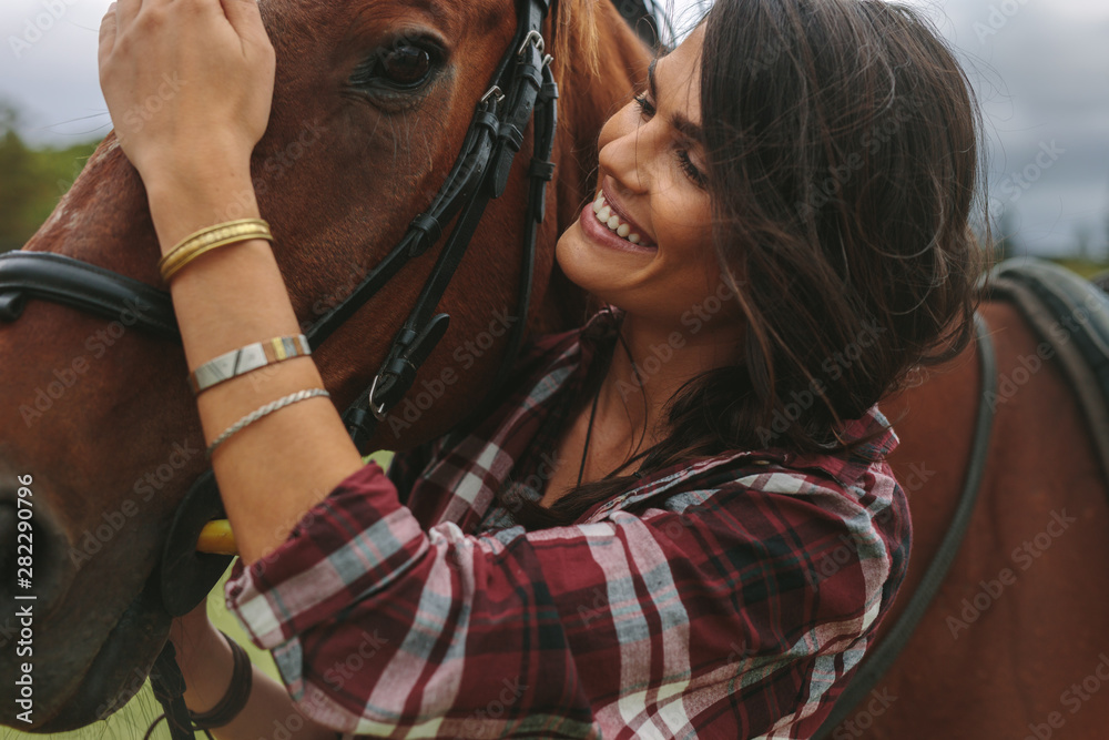 Smiling woman petting her horse