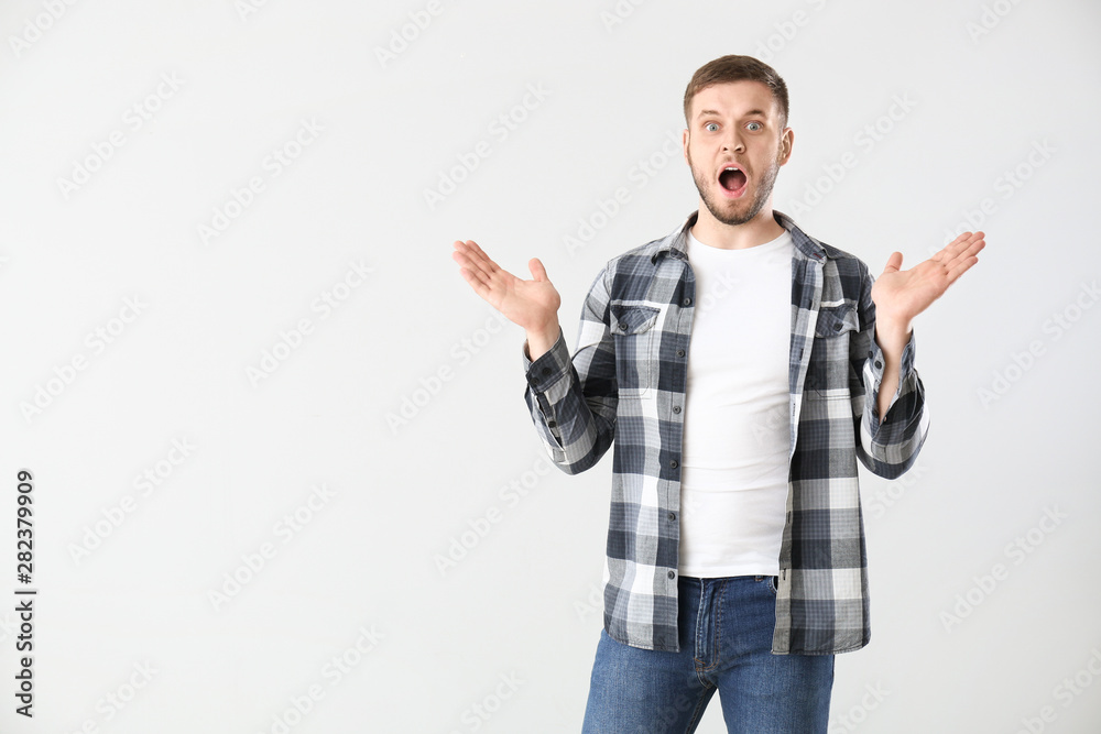 Shocked young man on light background