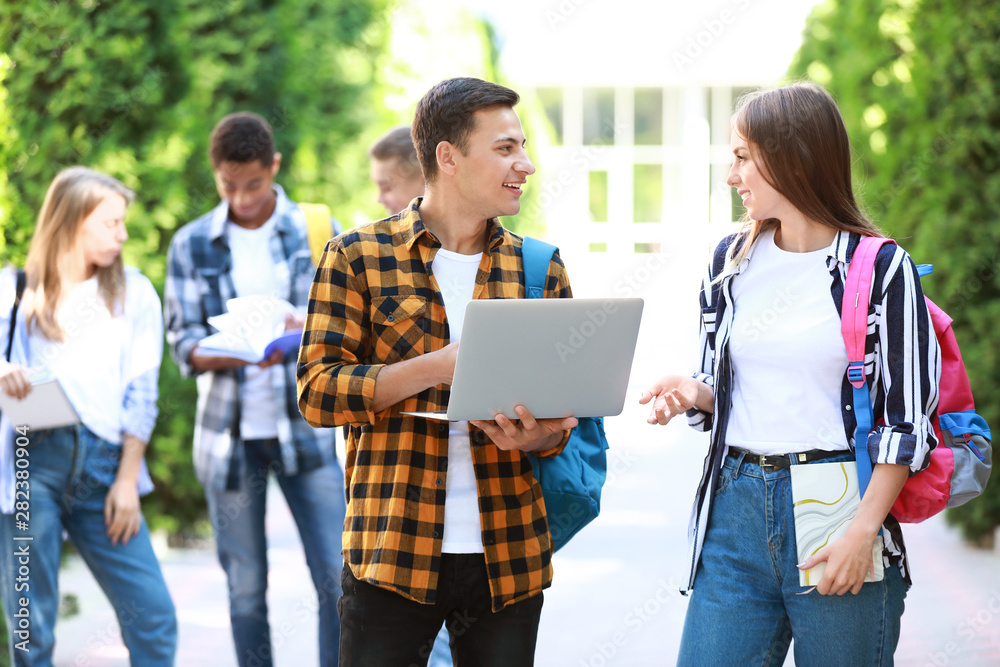 Young students with laptop outdoors