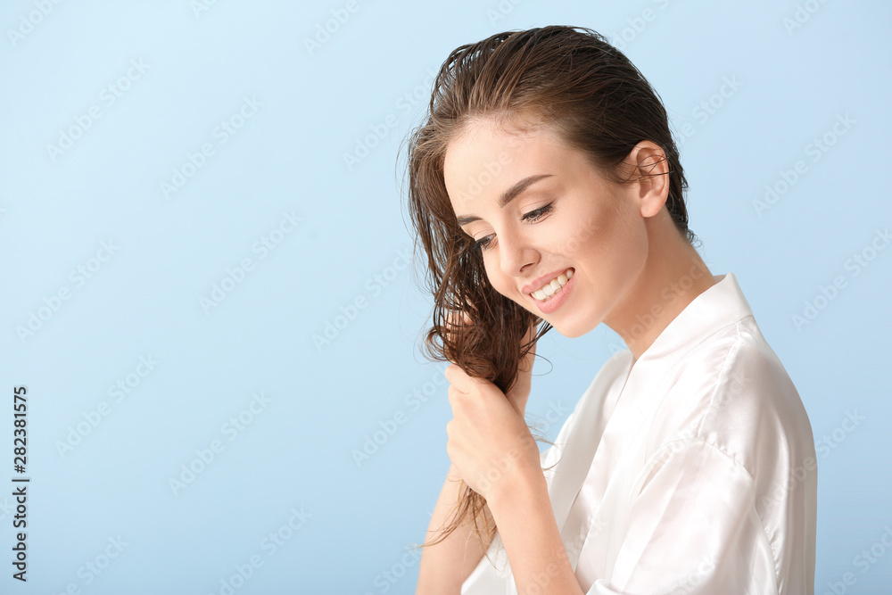 Beautiful young woman after washing hair against color background