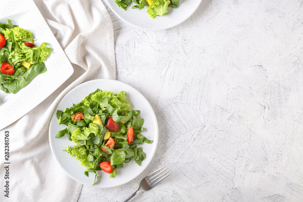 Plates with fresh tasty salad on light table