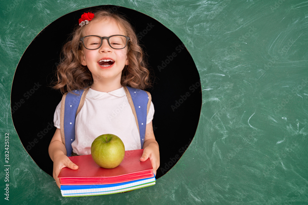 Kid in class on background of chalkboard.