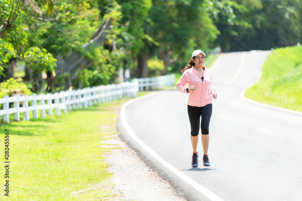 Sporty asian woman runner running and jogging through the road.  Outdoor Workout in a Park. Weight L