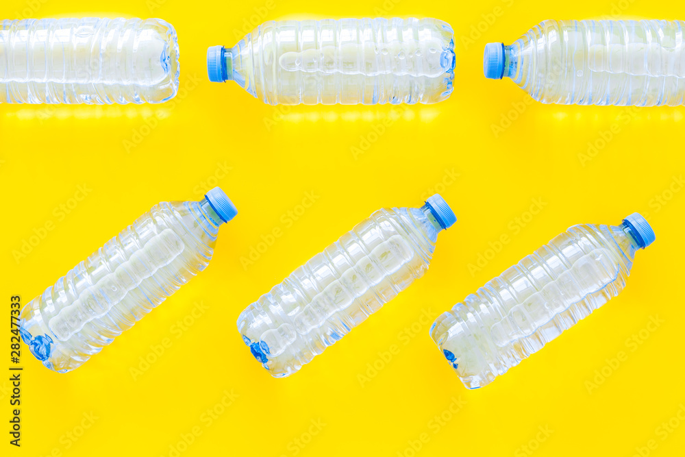 empty plastic bottles for pure water on yellow background top view pattern