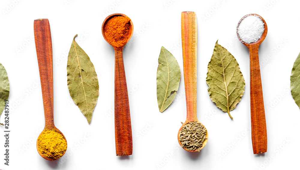 spices in wooden spoons on white background top view