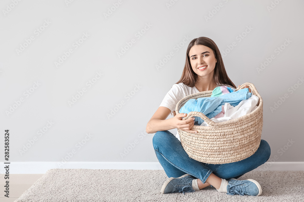 漂亮的年轻女人，洗衣服的衣服坐在白墙附近的地板上