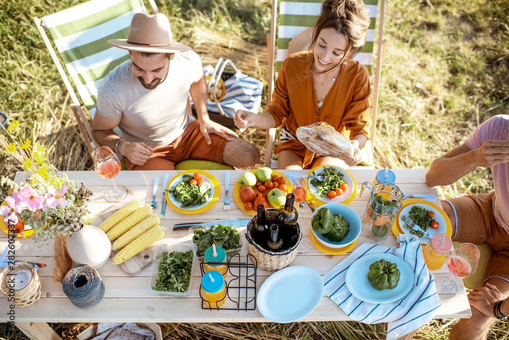 People having festive lunch in the garden with healthy food on the beautifully decorated table, top 