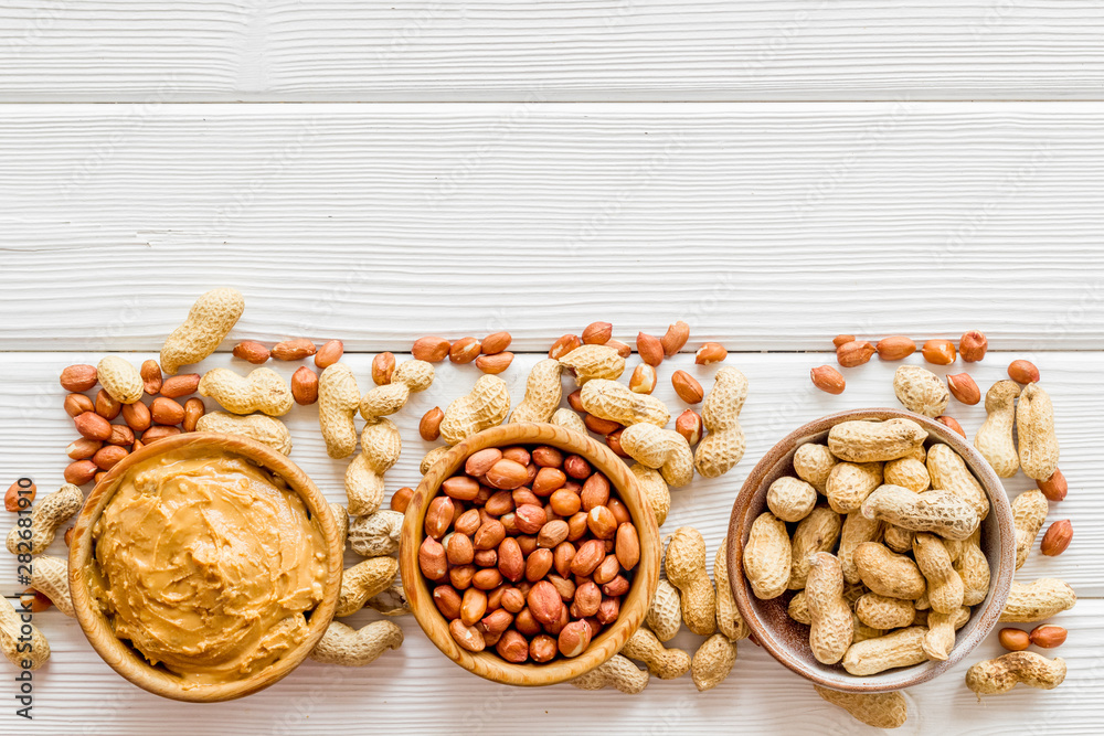 nuts in bowl for peanut butter for cooking breakfast at home on white wooden background top view moc