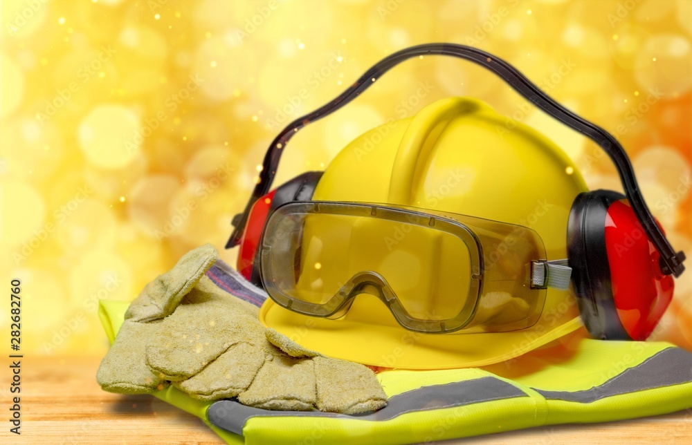 Safety helmet with earphones and goggles on construction background