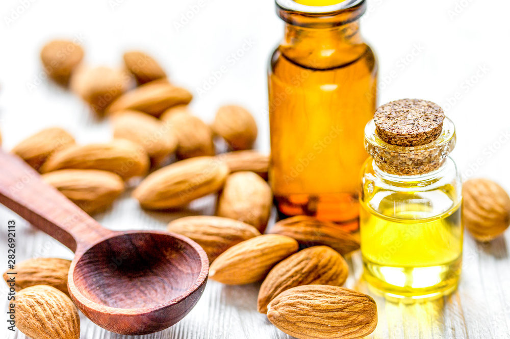 cosmetic and therapeutic almond oil on light wooden background