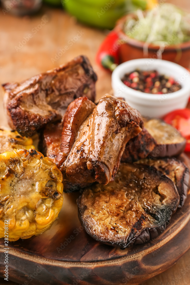 Tasty grilled meat with vegetables on board, closeup