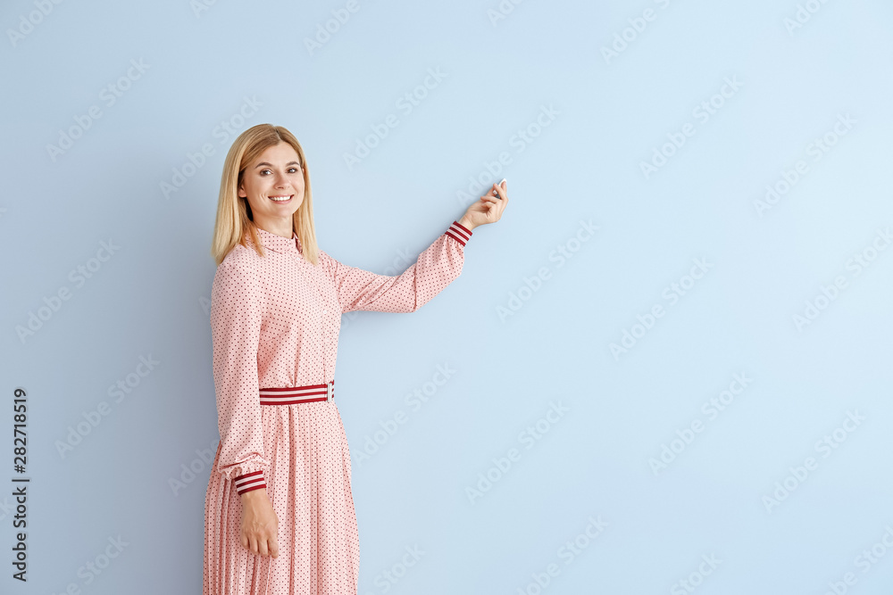 Beautiful female teacher with chalk on color background