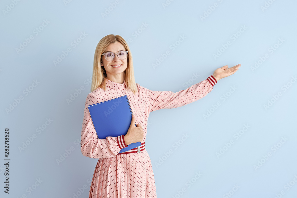 Beautiful female teacher showing something on color background