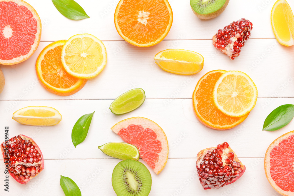 Different sliced citrus fruits on white wooden background