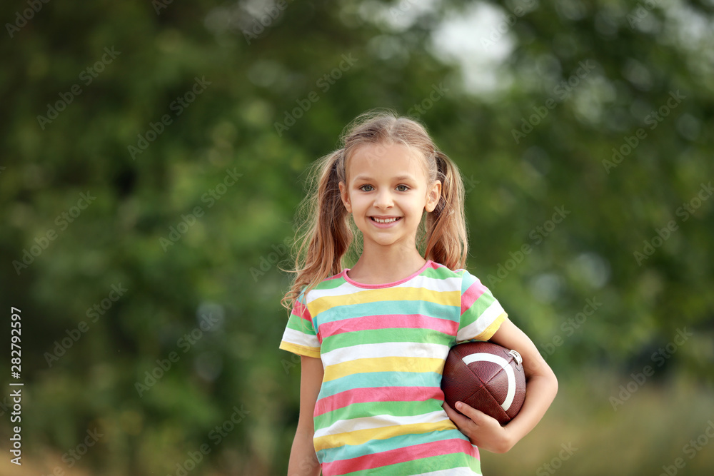 Portrait of cute little girl with rugby ball outdoors