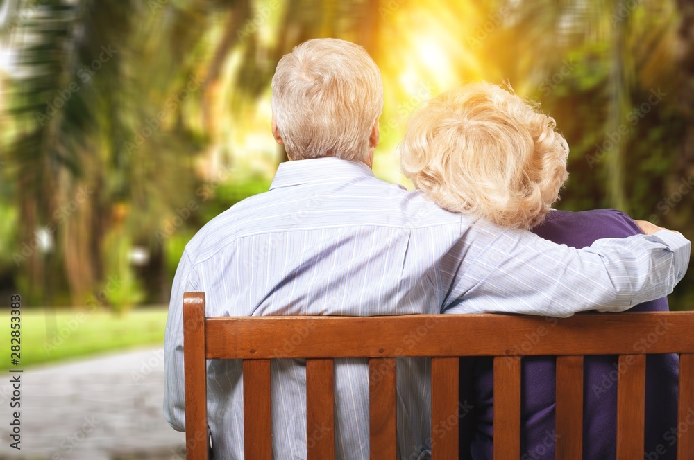 Portrait of happy senior couple in green blurred park background, bokeh