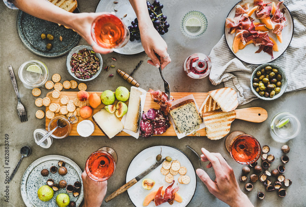 Mid-summer picnic with wine and snacks. Flat-lay of charcuterie and cheese board, rose wine, nuts, o