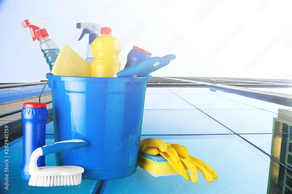 Plastic bottles, cleaning sponges and gloves on blue background