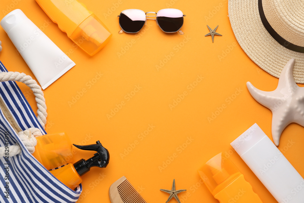 Beach accessories and sun protection cream on color background