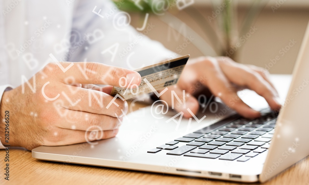 Closeup of a Man Typing on a Laptop and Holding a Credit Card