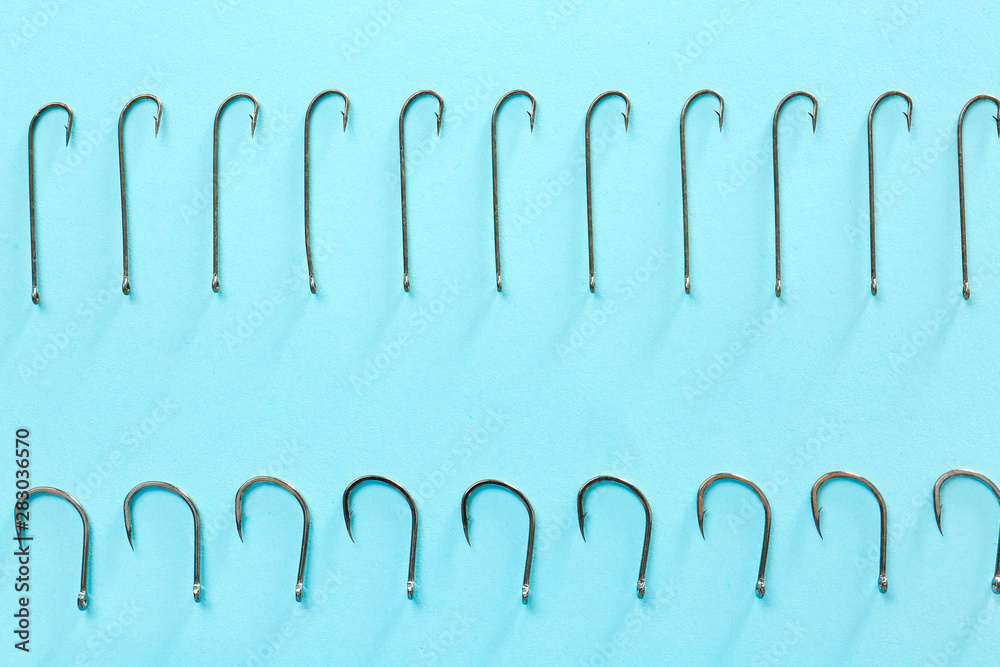 Different fishing hooks on color background